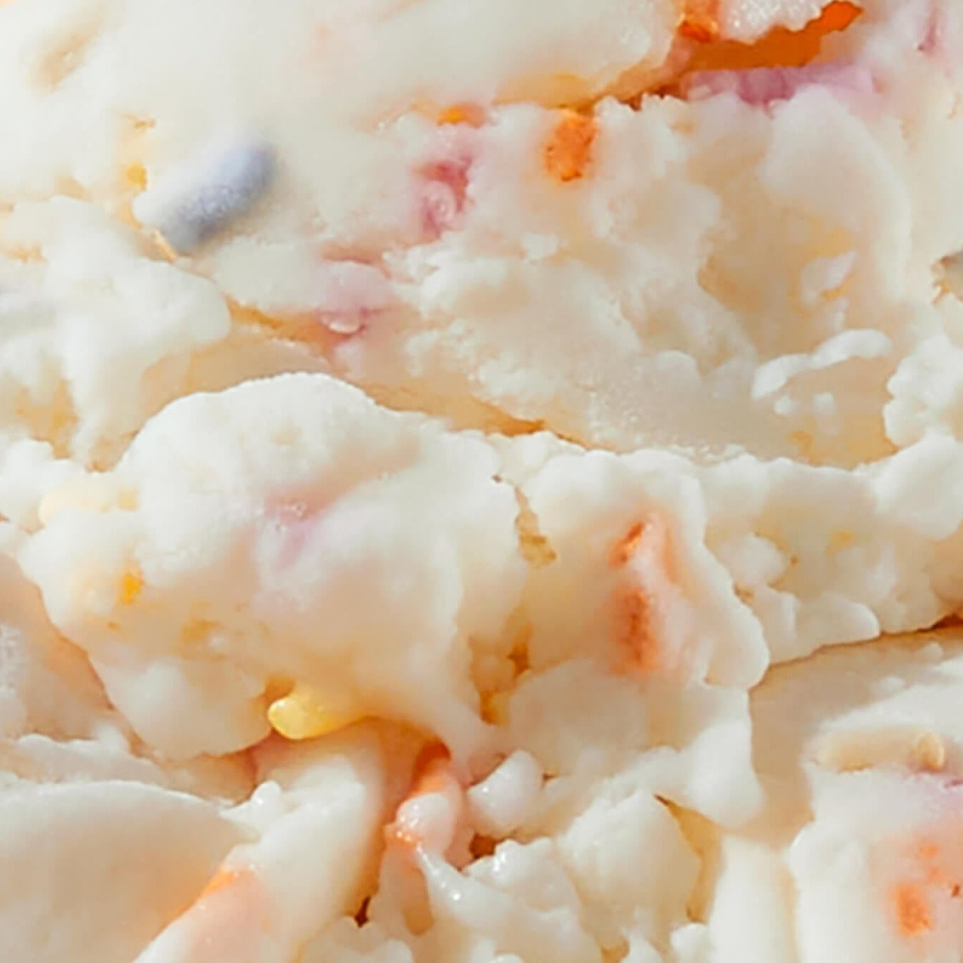 Extreme close-up texture shot of N!CK'S Birthday Cake light ice cream, showing white cake-flavored ice cream mixed with colorful sprinkles and creamy swirls.