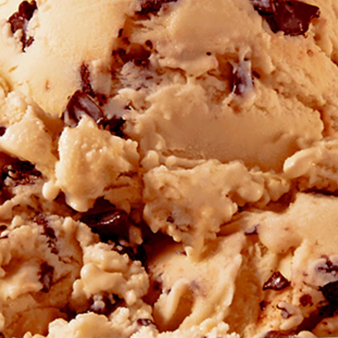 Extreme close-up texture shot of N!CK'S Coffee Chocolate Chip light ice cream, showing light coffee-colored ice cream with visible dark chocolate chip chunks.